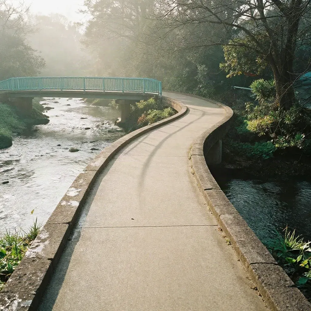 Overhead creekside loop path under a footbridge in morning mist